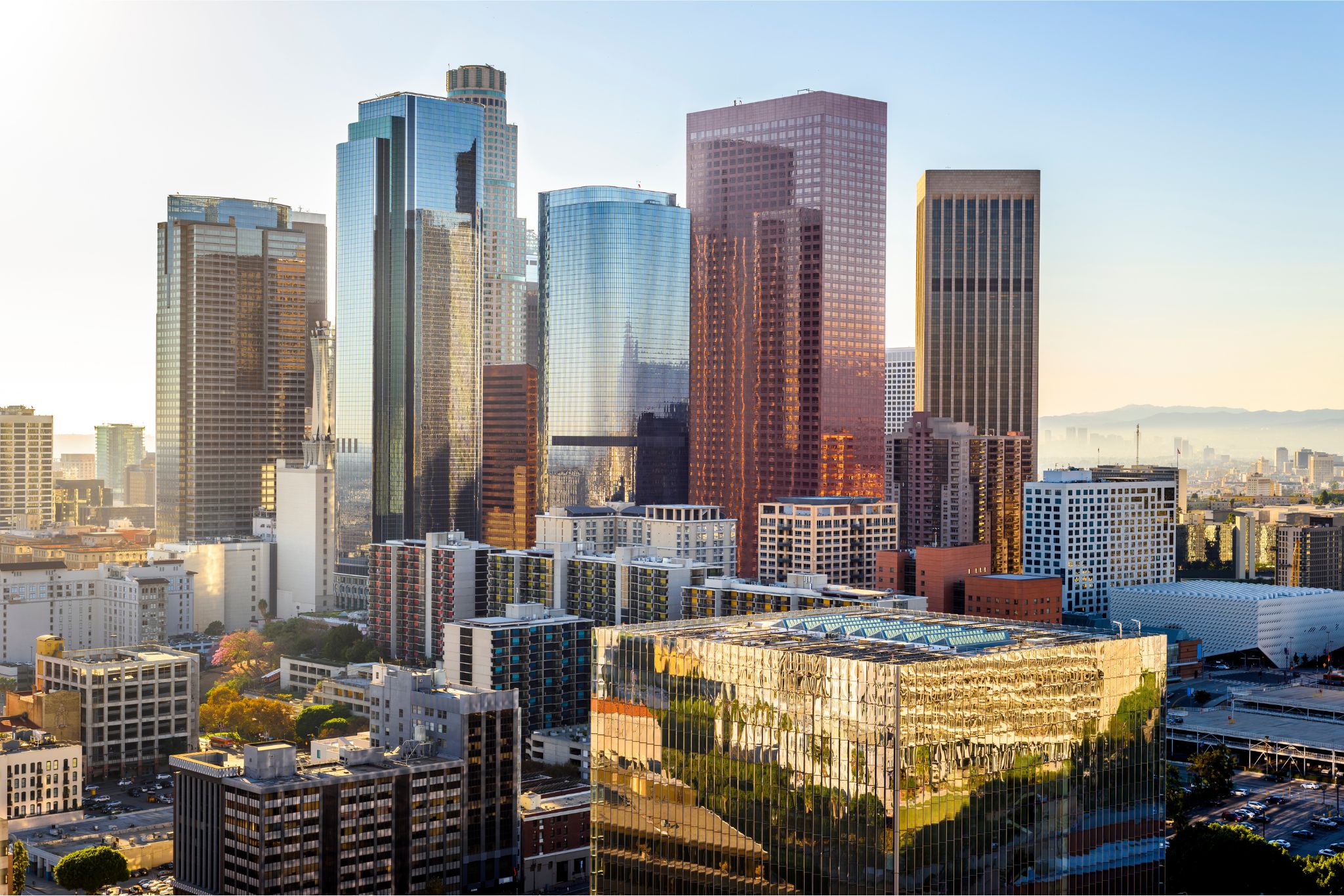 Downtown skyline of tall glass skyscrapers reflecting sunlight at dusk.